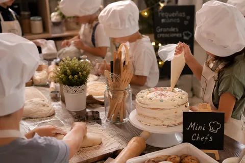 Niño decorando un pequeño pastel con la guía de un adulto